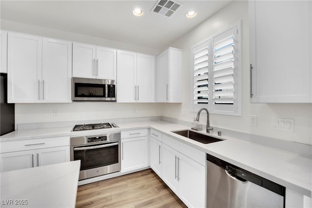 kitchen with appliances with stainless steel finishes, light countertops, and a sink