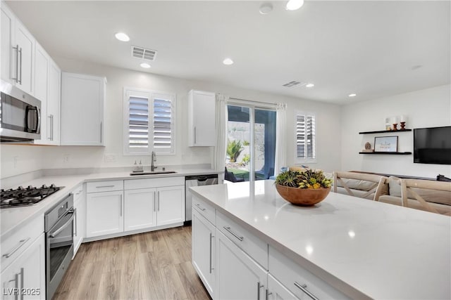 kitchen featuring a sink, white cabinets, stainless steel appliances, and light countertops