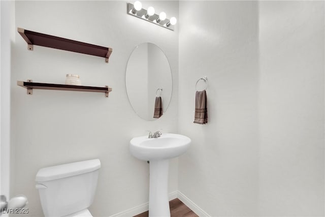 bathroom with toilet, baseboards, and wood finished floors