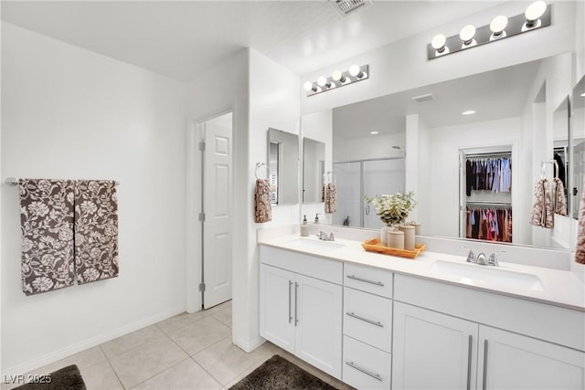 full bath featuring a spacious closet, a stall shower, a sink, and tile patterned floors