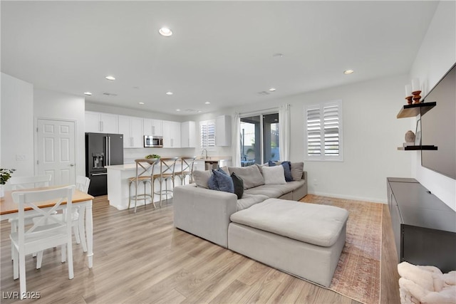 living area with baseboards, light wood-style flooring, and recessed lighting