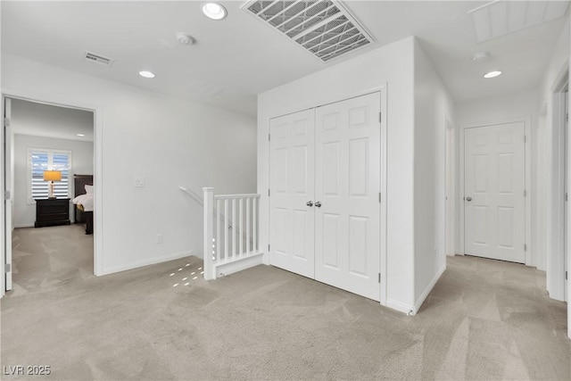 hall featuring visible vents, light carpet, an upstairs landing, and baseboards