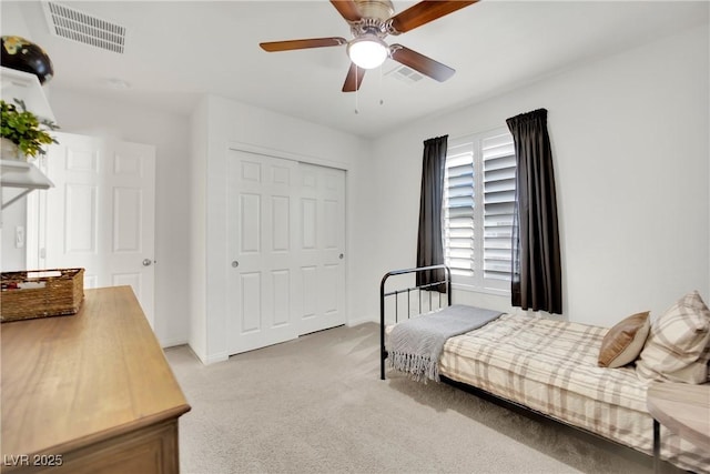 bedroom with a closet, visible vents, a ceiling fan, and light colored carpet