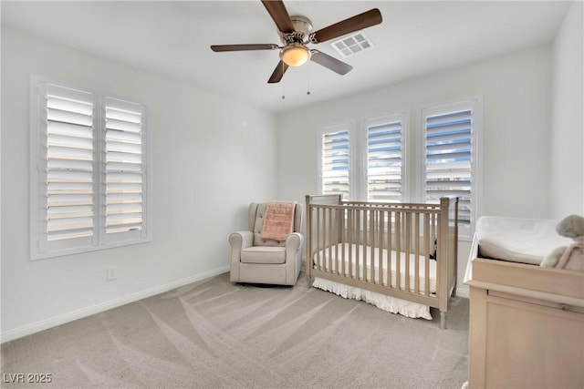 bedroom featuring ceiling fan, light carpet, visible vents, baseboards, and a crib