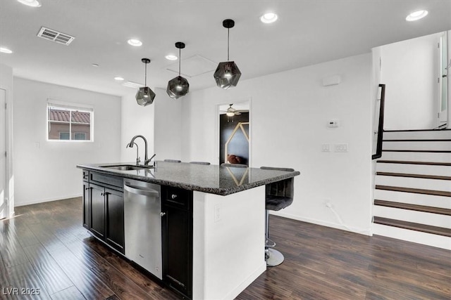 kitchen featuring visible vents, hanging light fixtures, stainless steel dishwasher, a sink, and an island with sink