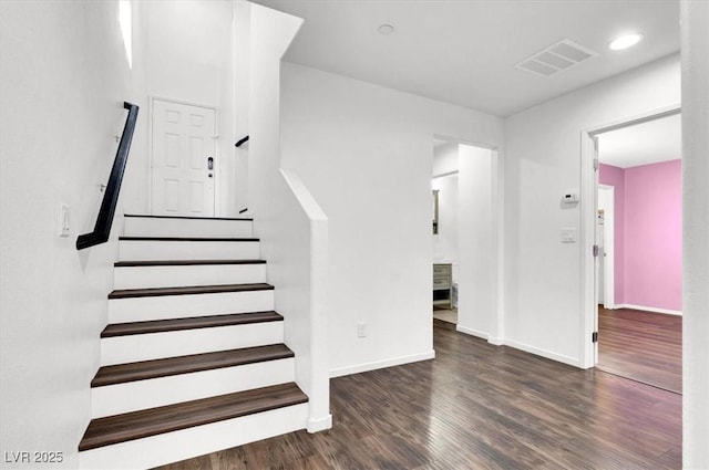 staircase featuring wood finished floors, visible vents, and baseboards