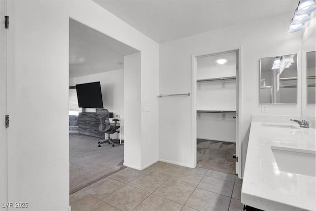 bathroom with double vanity, baseboards, a sink, and tile patterned floors