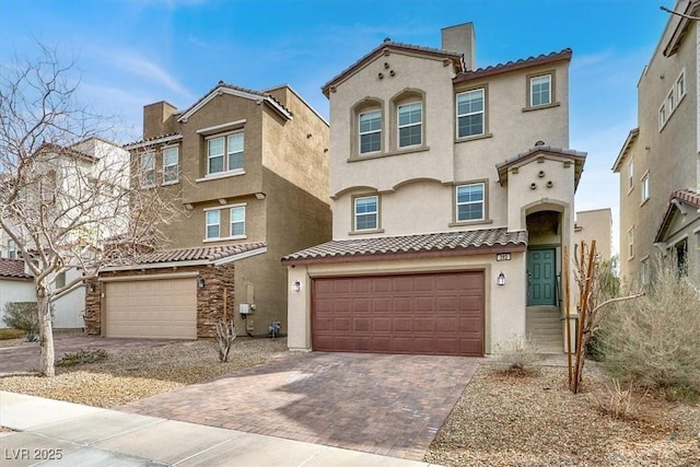 mediterranean / spanish-style house featuring a tile roof, decorative driveway, and stucco siding