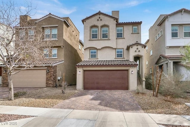 view of front of house featuring an attached garage, a tile roof, decorative driveway, and stucco siding