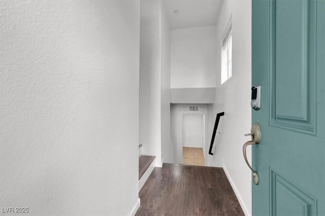 corridor with stairs, visible vents, baseboards, and wood finished floors