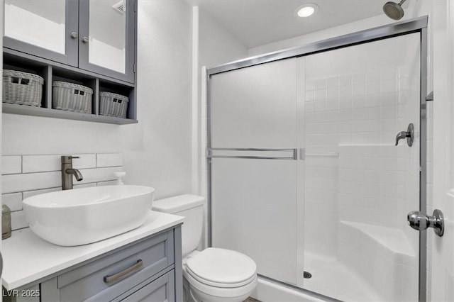 bathroom featuring tasteful backsplash, a shower stall, toilet, and vanity