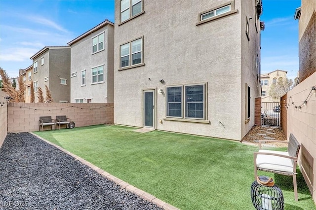 rear view of property featuring a lawn, a fenced backyard, and stucco siding