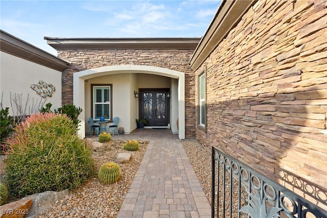 property entrance with french doors, stone siding, and stucco siding