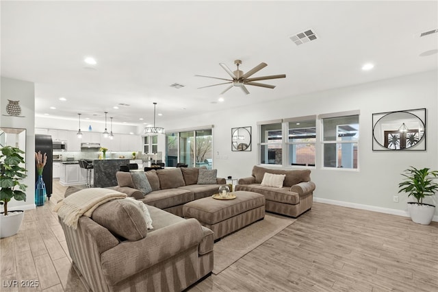 living room with light wood-type flooring, visible vents, baseboards, and recessed lighting