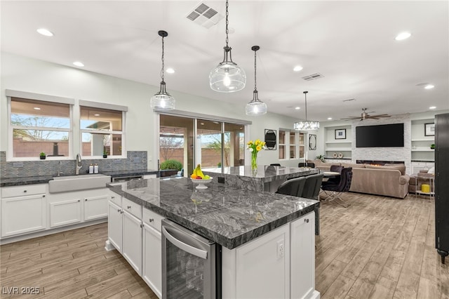 kitchen featuring visible vents, wine cooler, a large fireplace, and decorative backsplash