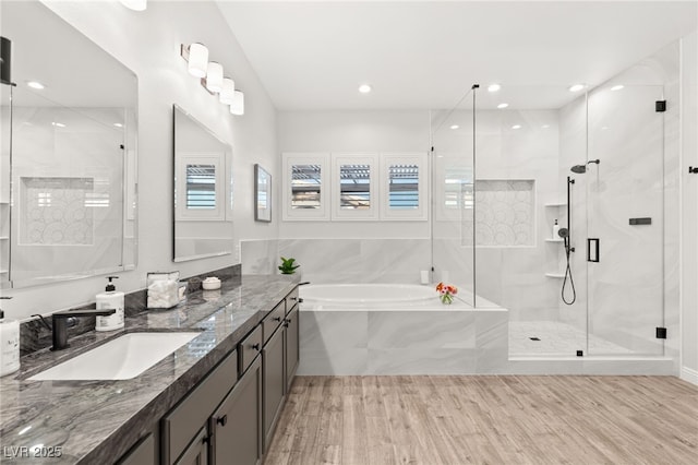 bathroom featuring a garden tub, a stall shower, wood finished floors, recessed lighting, and vanity