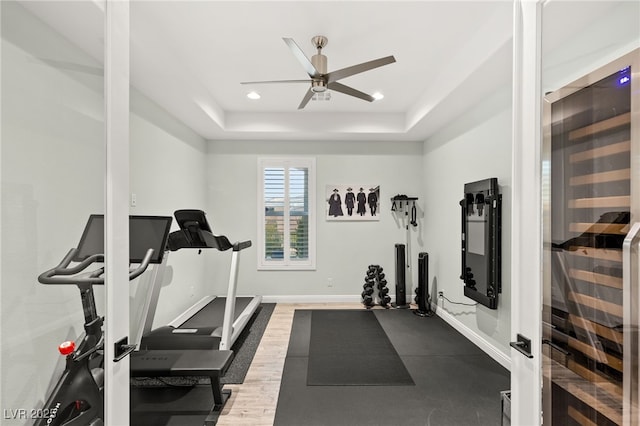 exercise area featuring beverage cooler, baseboards, recessed lighting, ceiling fan, and a raised ceiling