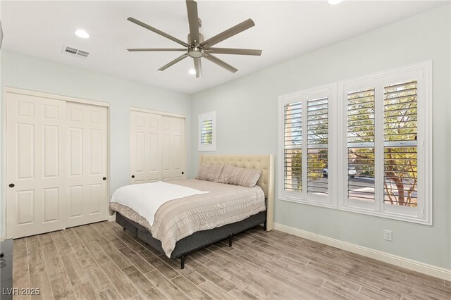 bedroom featuring visible vents, baseboards, recessed lighting, light wood-style floors, and two closets