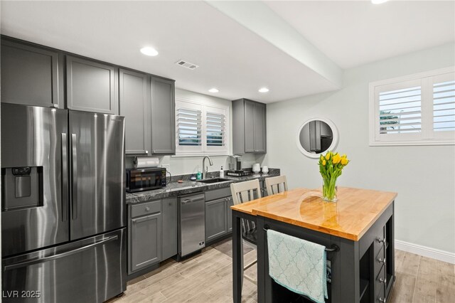 kitchen with gray cabinetry, stainless steel appliances, and a sink