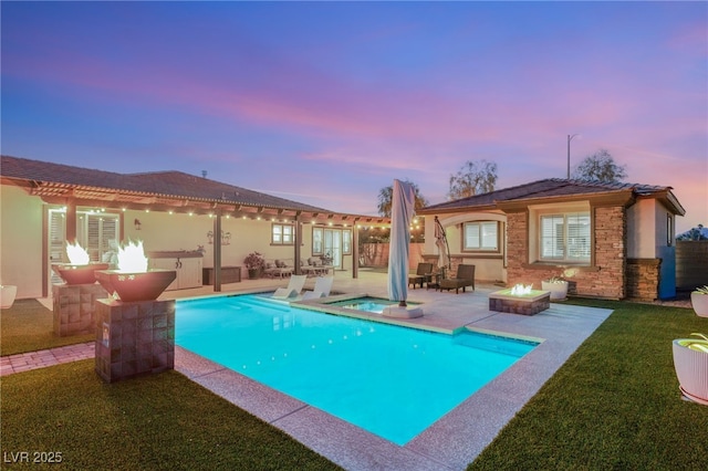 outdoor pool featuring a patio, a fire pit, a lawn, and an in ground hot tub