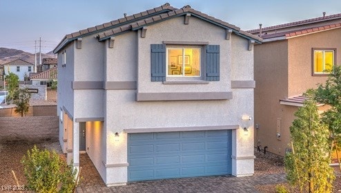 view of front of property with an attached garage, a tile roof, decorative driveway, and stucco siding