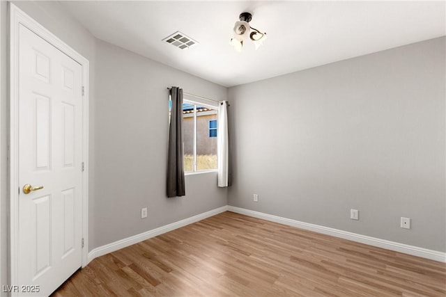 spare room with light wood-style floors, visible vents, and baseboards