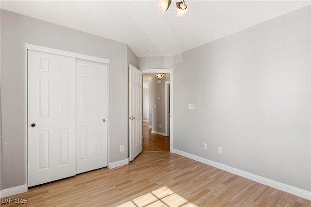 unfurnished bedroom featuring a closet, baseboards, and light wood finished floors