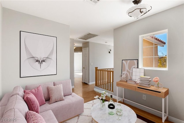 living area featuring visible vents, baseboards, and wood finished floors