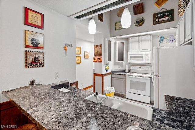 kitchen with a peninsula, white appliances, a sink, white cabinetry, and decorative light fixtures