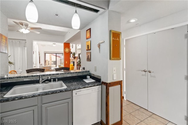 kitchen featuring dark countertops, gray cabinetry, white dishwasher, and a sink