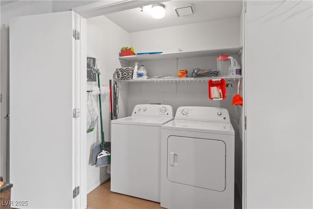 washroom featuring light wood finished floors, laundry area, and separate washer and dryer