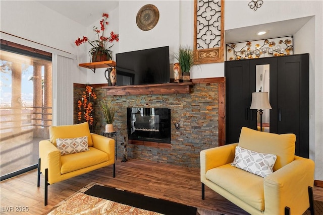 sitting room featuring lofted ceiling, a fireplace, and wood finished floors