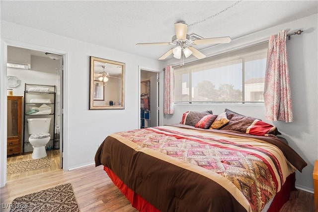 bedroom featuring a textured ceiling, a ceiling fan, baseboards, light wood-type flooring, and ensuite bath