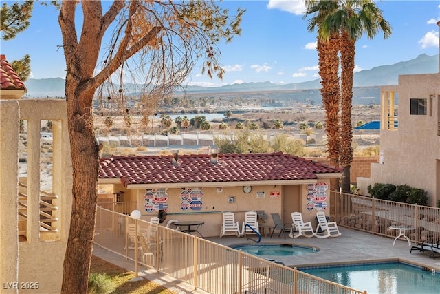 pool featuring fence, a mountain view, a community hot tub, and a patio