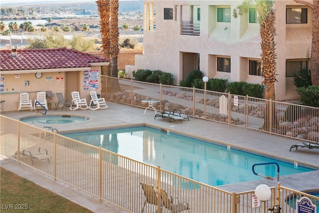 pool with a community hot tub, a patio, and fence