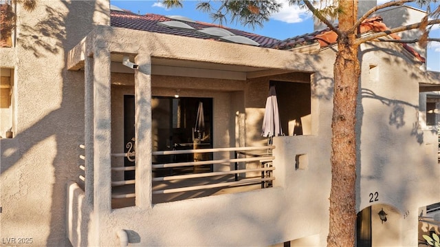 view of exterior entry with a tile roof and stucco siding