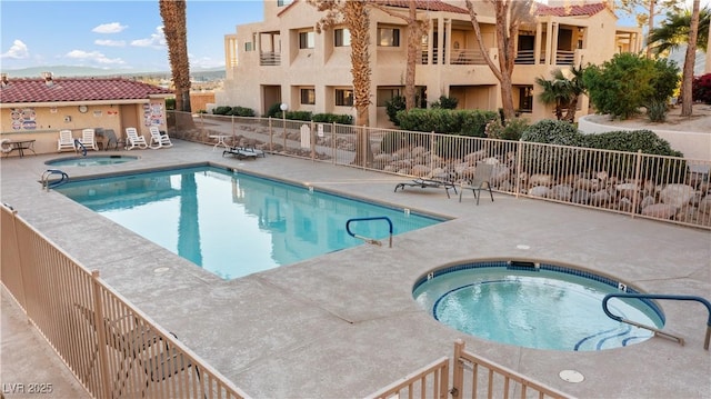 pool with a patio area, fence, and a community hot tub