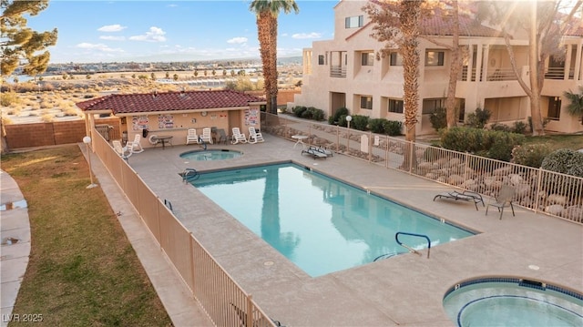 community pool featuring a patio area, fence, and a hot tub