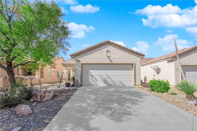 mediterranean / spanish-style house with stucco siding, concrete driveway, an attached garage, and a tile roof