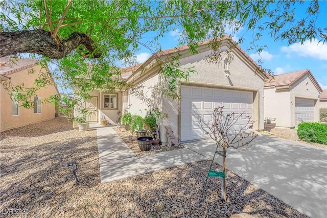 mediterranean / spanish home featuring stucco siding, an attached garage, a tile roof, and driveway