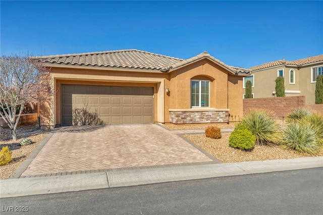 view of front of home featuring a garage, a tile roof, stone siding, decorative driveway, and stucco siding