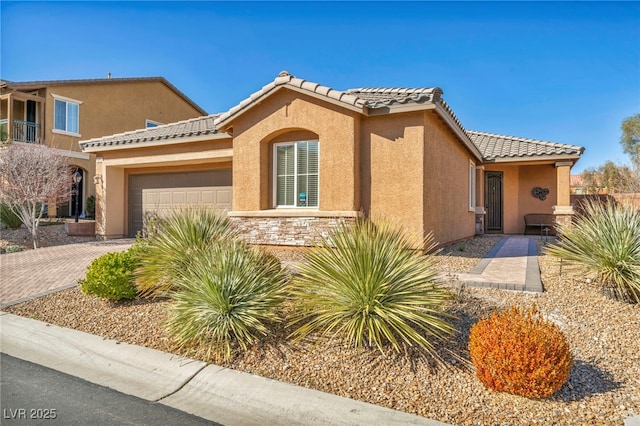 mediterranean / spanish house with a garage, stone siding, a tile roof, decorative driveway, and stucco siding