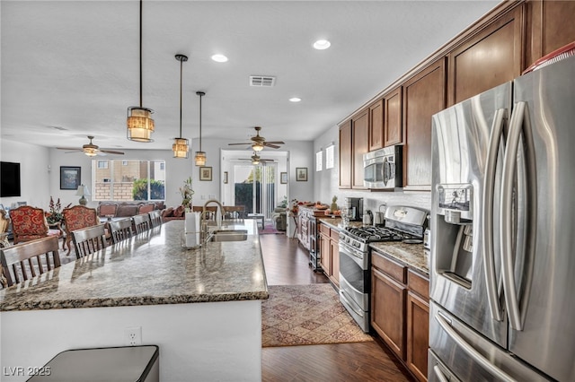 kitchen with stainless steel appliances, dark wood-style flooring, a sink, open floor plan, and an island with sink