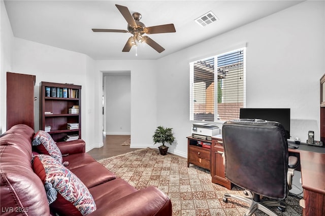 office featuring a ceiling fan, visible vents, light wood-style floors, and baseboards