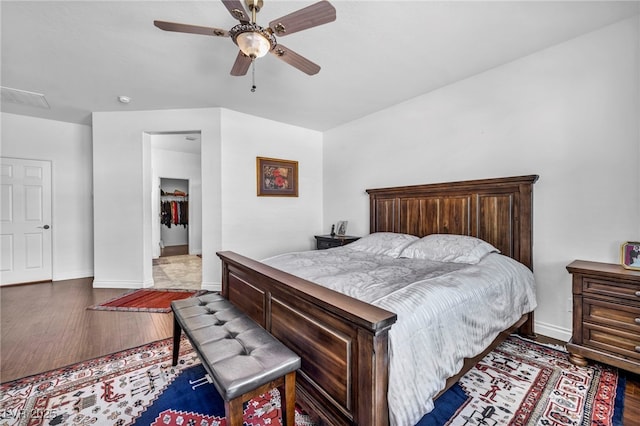 bedroom featuring a ceiling fan, attic access, baseboards, and wood finished floors