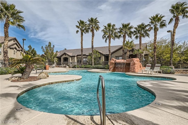 community pool with a patio area and fence