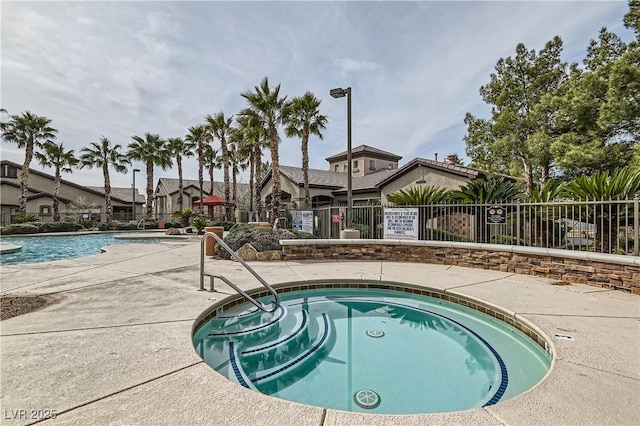 view of swimming pool featuring a residential view, fence, and a hot tub