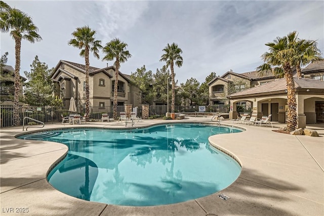 community pool with a patio area and fence