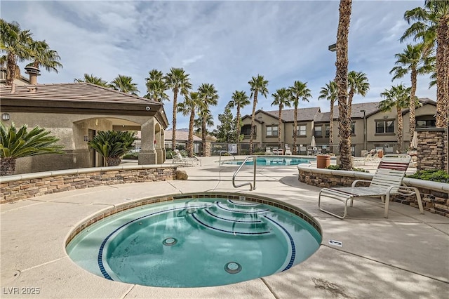 pool with a community hot tub, a patio area, fence, and a residential view