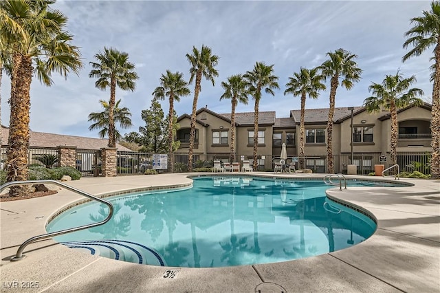 pool with a patio area, a residential view, and fence